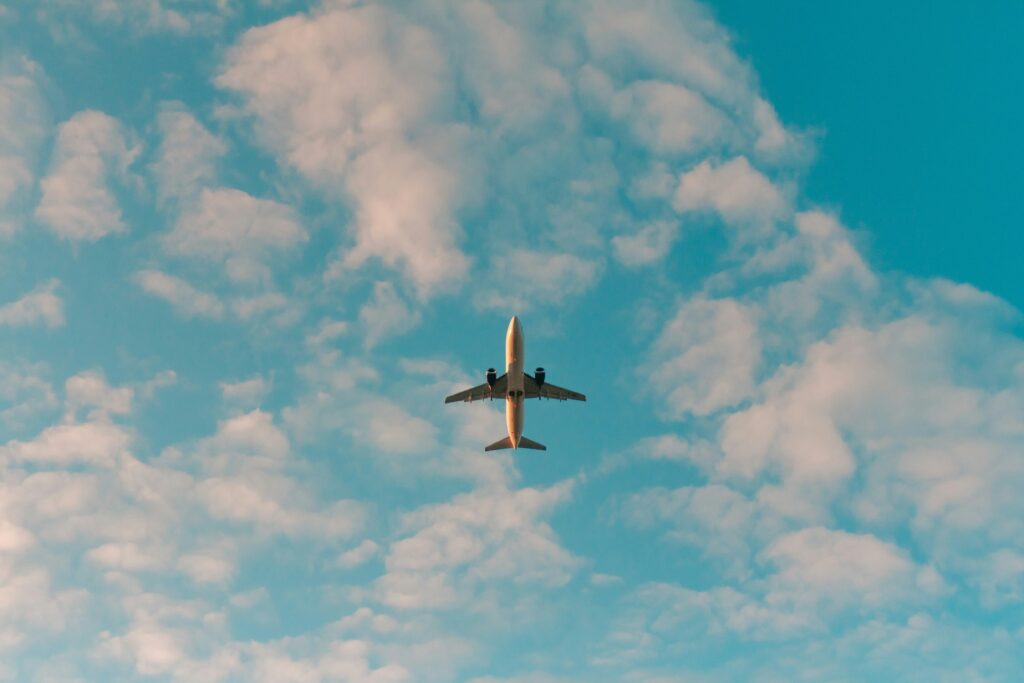 view looking into cloudy sky with airplane flying